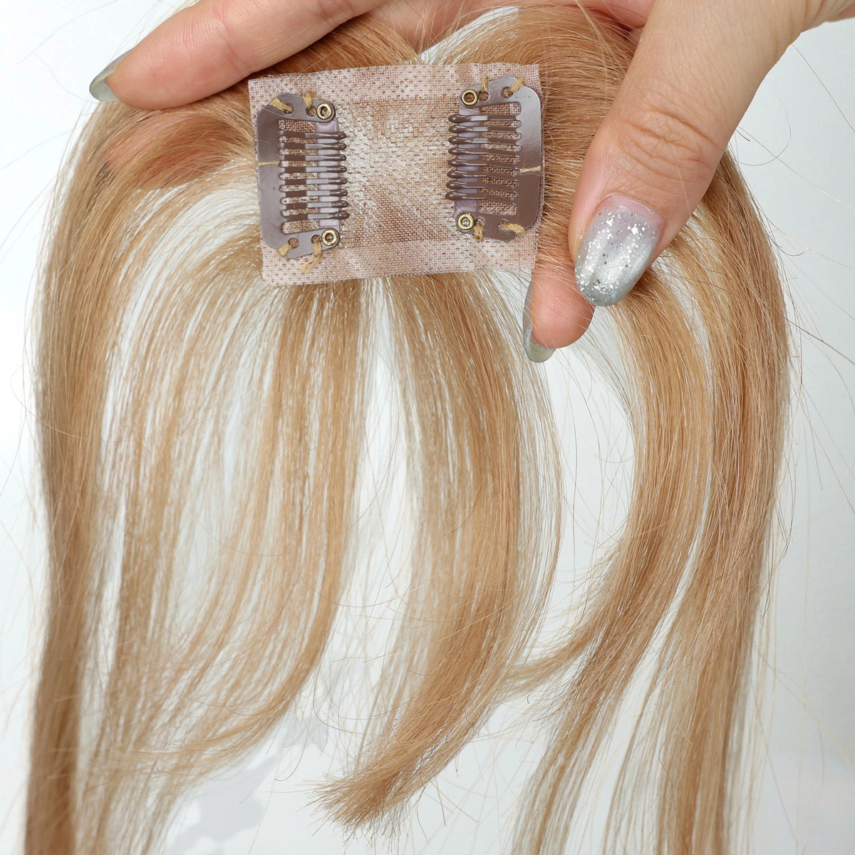 Underside of warm champagne blonde fringe hairpiece showing the base and two clips