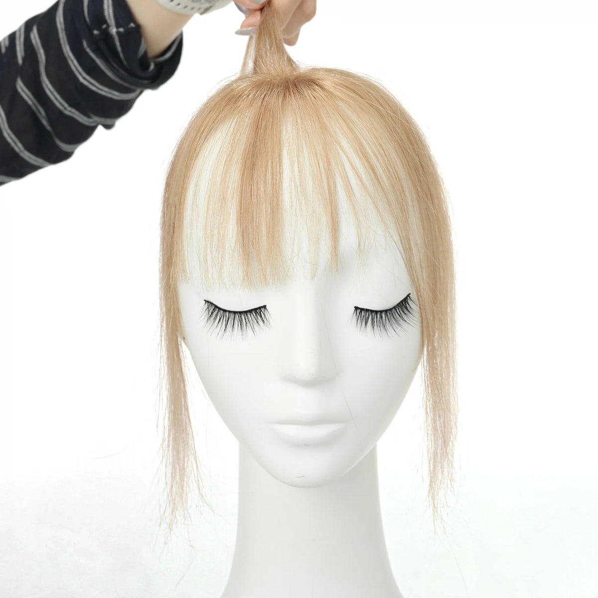 Warm champagne blonde clip-in fringe front view with the hairpiece held above a mannequin